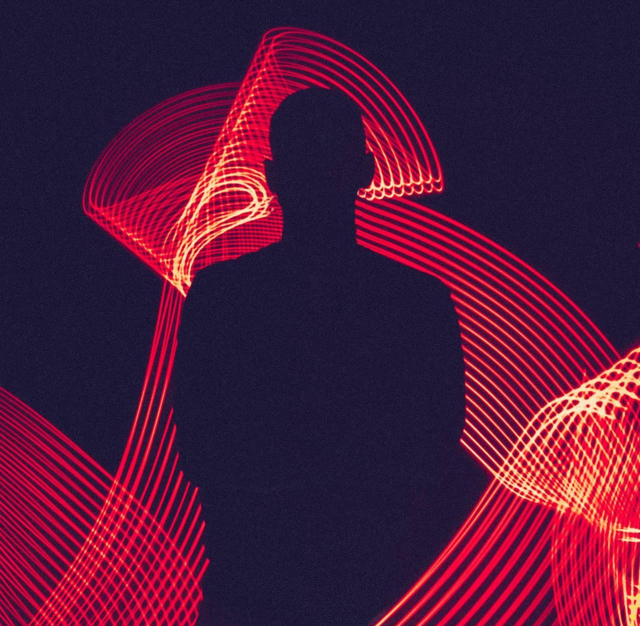 Silhouette of a person against a dark background surrounded by swirling red light trails.