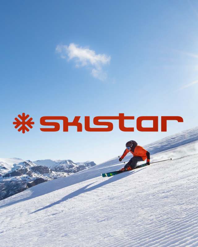 Skidåkare i orangeröd jacka åker ner för snöig sluttning under en klar blå himmel, SkiStar logotyp.