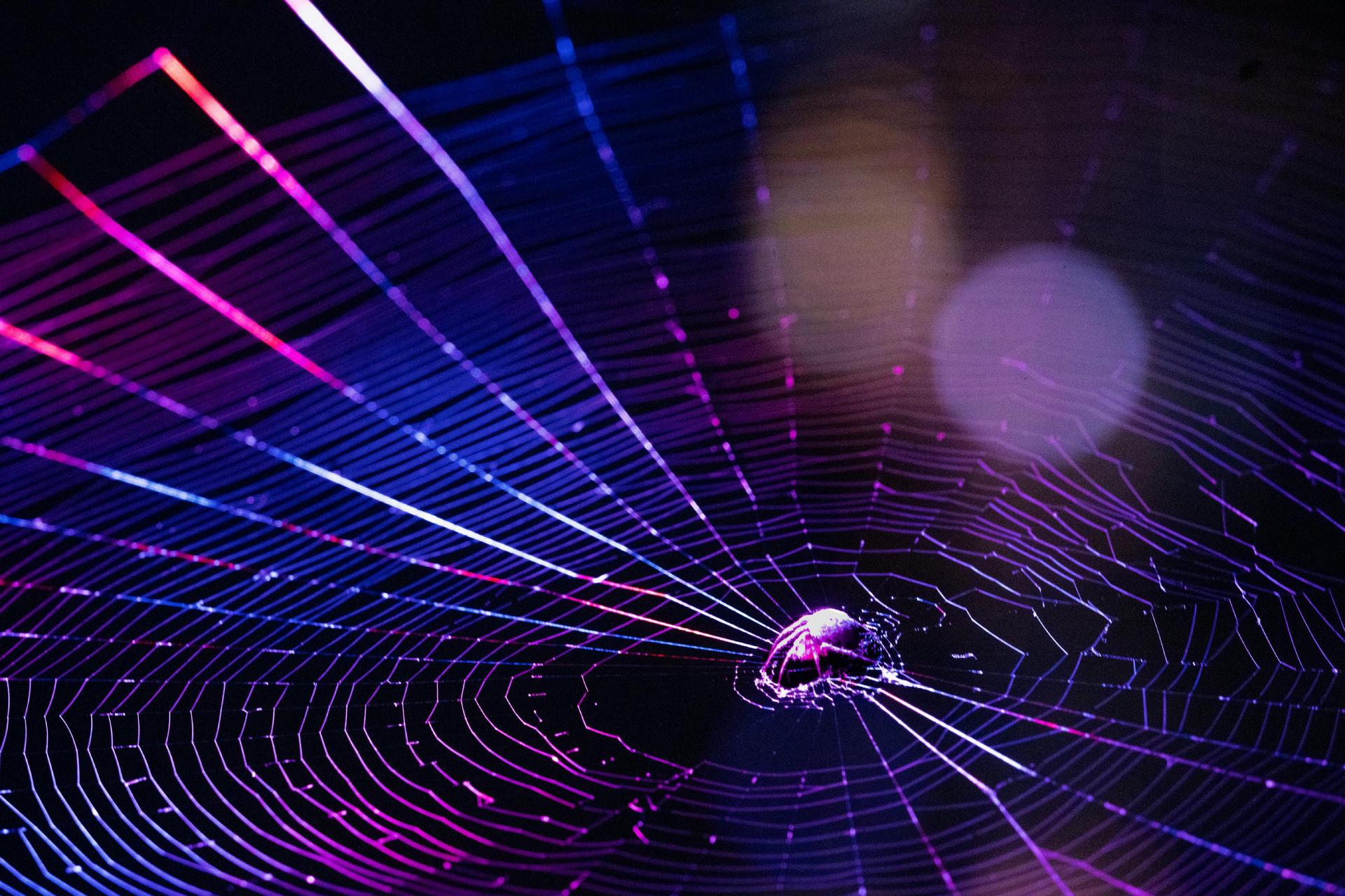 Glasbyggnadsfasad som speglar en färgglad solnedgång, med geometriska mönster och en blandning av varma och kalla toner.