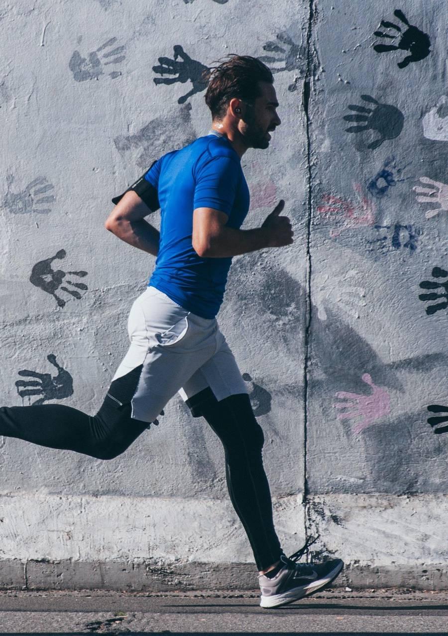 Kvinna i en beige klänning sitter på trappen, vinden blåser hennes hår över ansiktet, med färgglada skåp i bakgrunden.